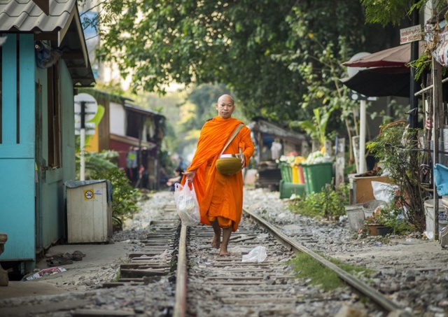 Nhà sư đi khất thực dọc một xóm đường tàu ở Bangkok, Thái Lan.