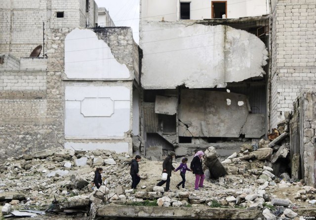 Trẻ em đi qua đống đổ nát của một tòa nhà ở Aleppo, Syria.