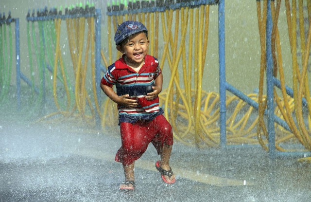 Em bé thích thú được phun nước trong lễ hội té nước Thingyan ở Yangon, Myanmar.