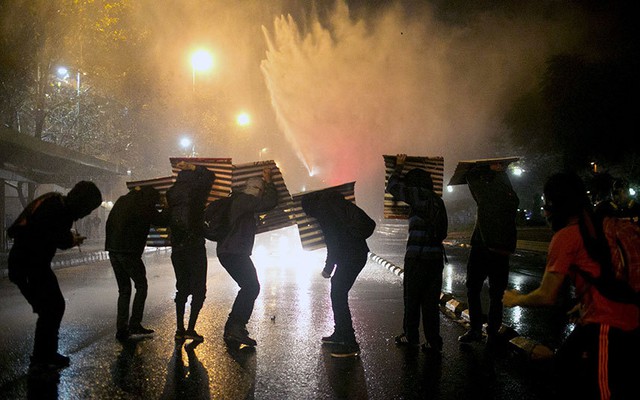 Sinh viên chống đỡ với vòi rồng phun nước của cảnh sát trong cuộc biểu tình ở Santiago, Chile.