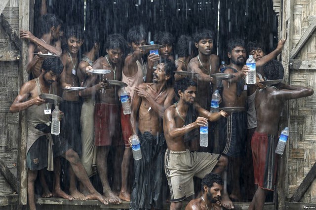 Những người nhập cư hứng nước mưa tại một tại một trại tị nạn ở ngoại ô thị trấn Maungdaw, Myanmar.