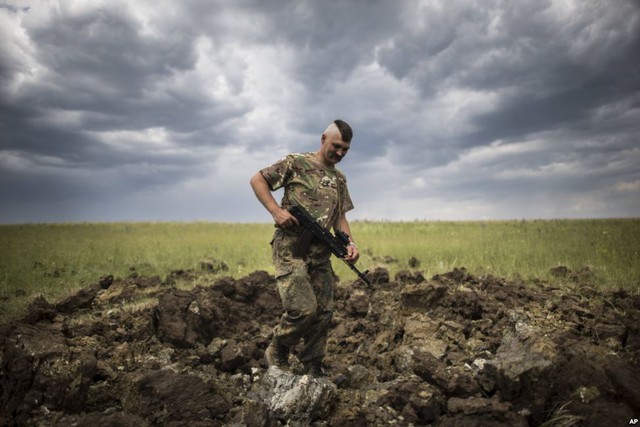 Quân nhân Ukraine kiểm ra một hố lớn do rocket Grad gây ra tại ngôi làng Toshkivka ở vùng Luhansk, miền đông Ukraine.