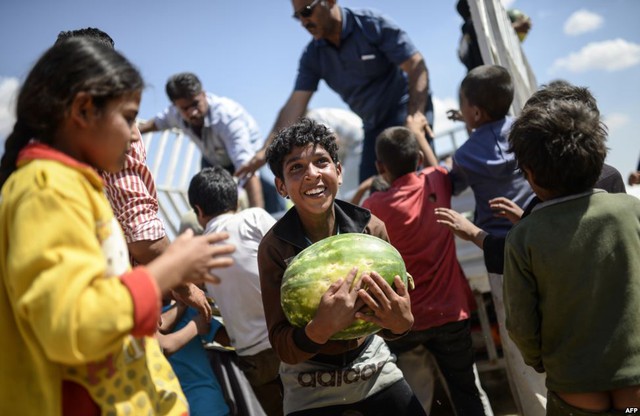 Cậu bé người Syria ôm quả dưa hấu được phân phát gần cửa khẩu Akcakale giáp biên giới với tỉnh Sanliurfa, Thổ Nhĩ Kỳ.