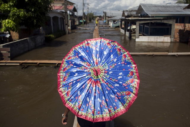 Người dân sử dụng lối đi tạm để qua đường phố ngập lụt tại Careiro da Varzea, bang Amazonas, Brazil.