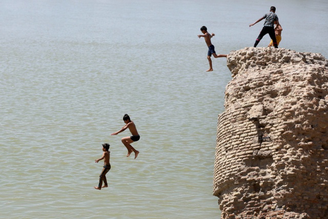 Trẻ em nhảy từ một tòa nhà cũ xuống sông Tigris để tắm mát trong một ngày nắng nóng ở Baghdad, Iraq.