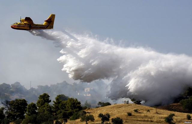 Người dân địa phương nhìn máy bay thả nước chữa cháy rừng tại vùng Argolida, Hi Lạp.