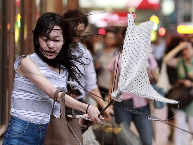 Một phụ nữ vất vả giữ ô khi đi trong gió mạnh do siêu bão Soudelor gây ra tại thành phố Đài Bắc, Đài Loan.