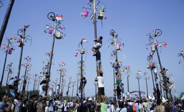 Người dân thi trèo cột mỡ để giành giải thưởng là xe đạp và nồi cơm điện tại lễ hội mừng quốc khánh ở Jakarta, Indonesia.