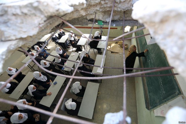 Các nữ sinh Palestine phải ngồi học trong lớp bị thủng mái tại trường Suhada Khouza ở Khan Younis, Dải Gaza.
