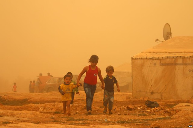 Trẻ em Syria dắt tay nhau đi trong bão cát tại một trại tị nạn ở ngoại ô thành phố Baalbek, Li Băng.