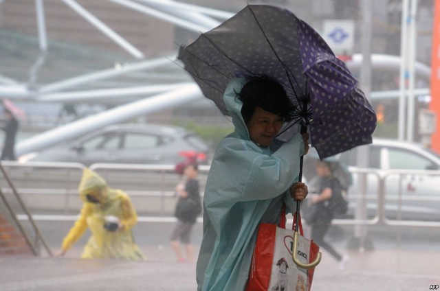 
Người dân di chuyển khó khăn trong mưa to và gió lớn do bão Dujuan gây ra tại thành phố Tân Bắc, Đài Loan.
