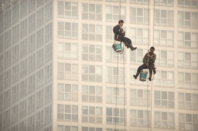 Công nhân vệ sinh cửa sổ kính các tòa nhà cao tầng làm việc trong bầu không khí ô nhiễm ở thành phố Bắc Kinh, Trung Quốc.
