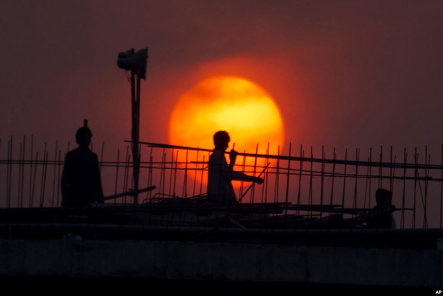 Công nhân làm việc trên một cây cầu lúc mặt trời lặn ở thành phố Islamabad, Pakistan.