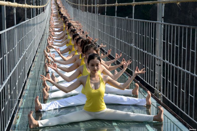 Các cô gái tập yoga trên cây cầu kính trong vườn quốc gia Shiniuzhai ở tỉnh Hồ Nam, Trung Quốc.