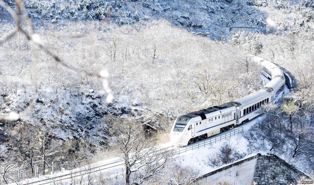 Đoàn tàu hỏa di chuyển qua sườn đồi phủ đầy tuyết trắng ở ngoại ô thành phố Bắc Kinh, Trung Quốc.