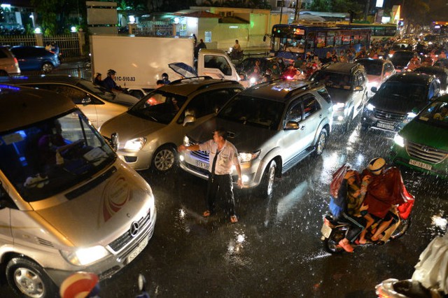 Một tài xế ô tô bất lực điều tiết giao thông giữa mưa - Ảnh: Hữu Khoa