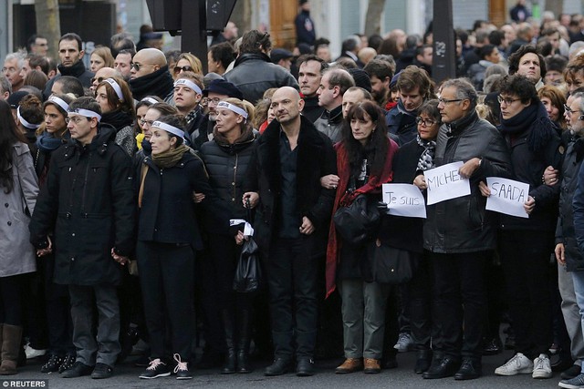 Gia quyến của 17 nạn nhân nắm tay nhau trên đường phố Paris trong một bản hành khúc (Marche Republicaine).