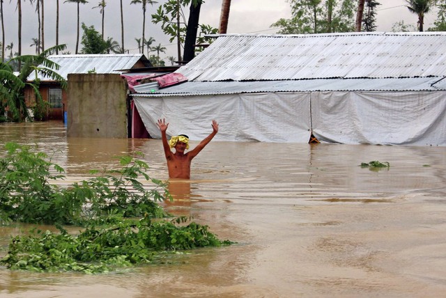 Người dân lội trong nước lũ do mưa lớn gây ra tại thị trấn Palo, tỉnh Samar, Philippines.