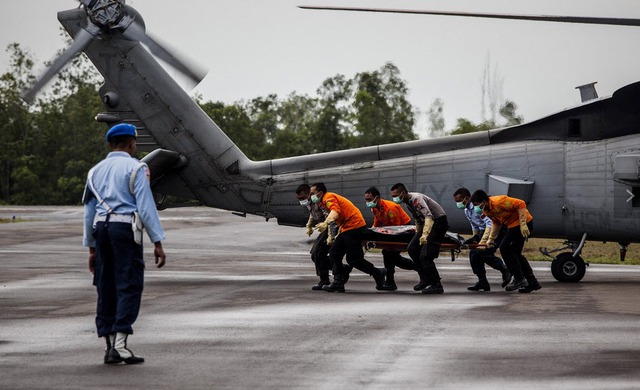 Các thành viên đội tìm kiếm và cứu hộ di chuyển thi thể một nạn nhân thiệt mạng trong vụ tai nạn máy bay QZ8501 của hãng hàng không AirAsia tại Căn cứ không quân ở Iskandar, Indonesia.