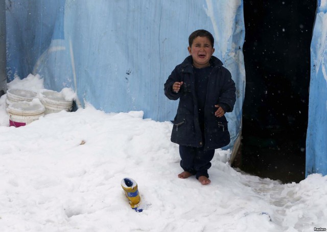 Cậu bé tị nạn người Syria òa khóc khi đứng chân trần trên tuyết bên ngoài túp lều tại một trại tị nạn ở Zahle, Li Băng.