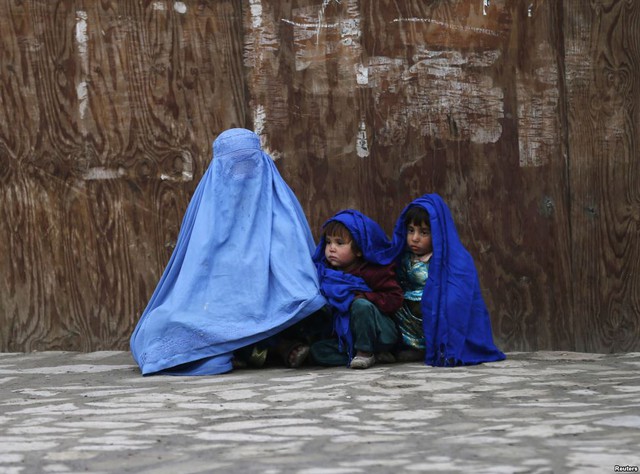 Người phụ nữ và con nhỏ ngồi chờ bắt xe trong một ngày lạnh giá ở Kabul, Afghanistan.