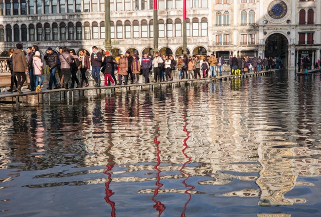 Du khách phải đi trên cầu để tránh nước ngập tại thành phố Venice, Italia.