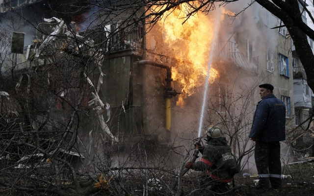 Lính cứu hỏa cố gắng dập tắt lửa trên tòa nhà chung cư bị trúng đạn pháo ở ngoại ô thành phố Donetsk, miền đông Ukraine.