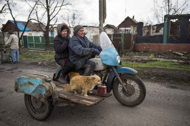 Một cặp vợ chồng cùng con chó của họ đi trên chiếc xe ba bánh tại ngôi làng Nikishino thuộc Cộng hòa nhân dân Donetsk tự xưng ở miền đông Ukraine.