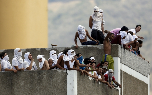 Các phạm nhân đứng trên mái của trụ sở cảnh sát quốc gia trong cuộc bạo loạn ở Caracas, Venezuela.