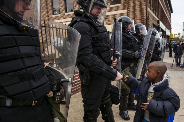 Một cậu bé da màu chào cảnh sát chống bạo động đứng bảo vệ ở Baltimore, Maryland, Mỹ.