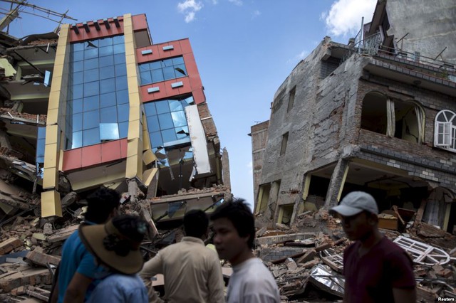 Mọi người đi qua những ngôi nhà bị sập sau trận động đất mạng 7,3 độ richter ở Kathmandu, Nepal.