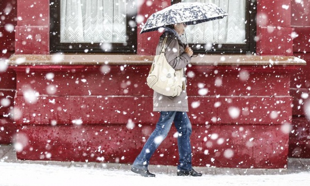 Người phụ nữ đi bộ dưới mưa tuyết trên đường phố ở Steinach, Áo.