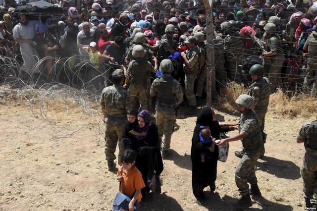 Binh sĩ Thổ Nhĩ Kỳ giúp đỡ những người tị nạn Syria khi họ vượt qua biên giới vào thị trấn Akcakale, tỉnh Sanliurfa, hổ Nhĩ Kỳ.
