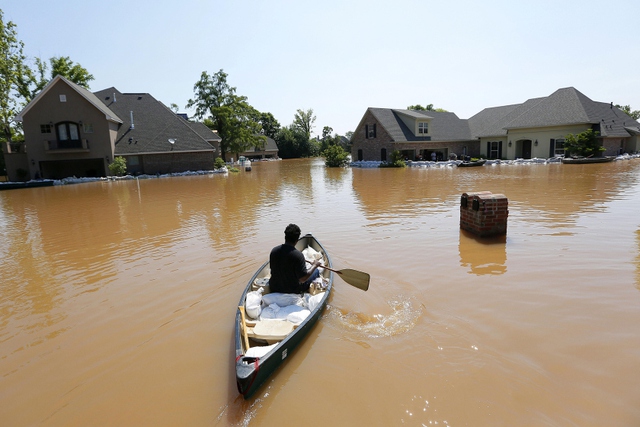 Người đàn ông chở những bao tải cát tới một ngôi nhà bị bao vây bởi nước lũ ở Shreveport, bang Louisiana, Mỹ.