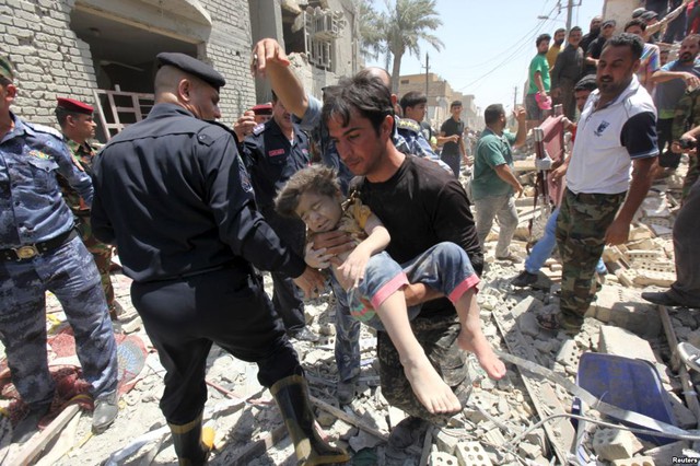 Người đàn ông đưa em bé bị thương khỏi đống đổ nát sau khi máy bay chiến đấu của quân đội Iraq thả bom nhầm xuống quận Niiriya ở thủ đô Baghdad.