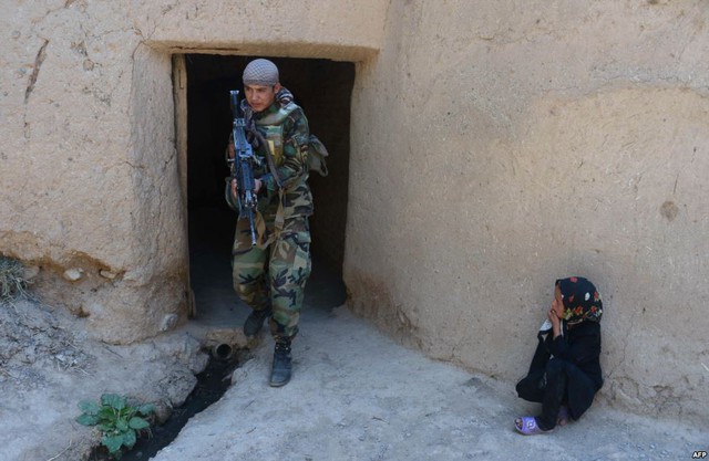 Bé gái nhìn lính đặc nhiệm của quân đội quốc gia Afghanistan đi tuần tra tại quận Gozara ở Herat.