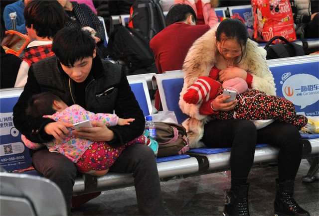 
Hành khách giết thời gian bằng Smartphone ở nhà ga phía Tây Bắc Kinh. Người phụ nữ này thậm chí còn dán mắt vào điện thoại trong lúc đang cho con bú.
