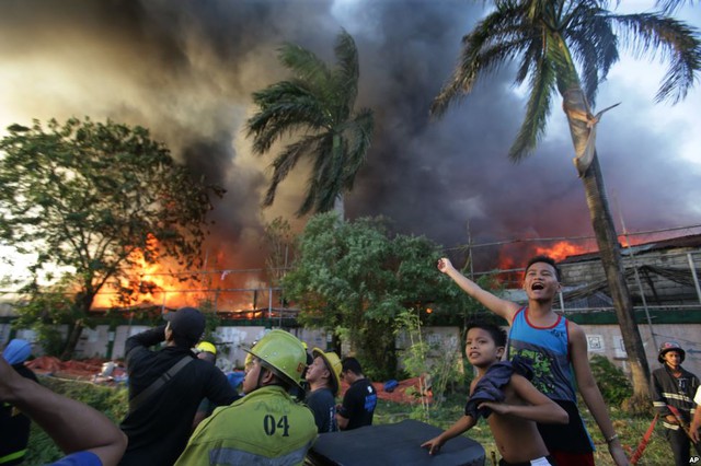 Người dân ra hiệu cho trực thăng thả nước để dập tắt đám chạy tại khu dân cư ở Mandaluyong, Philippines.