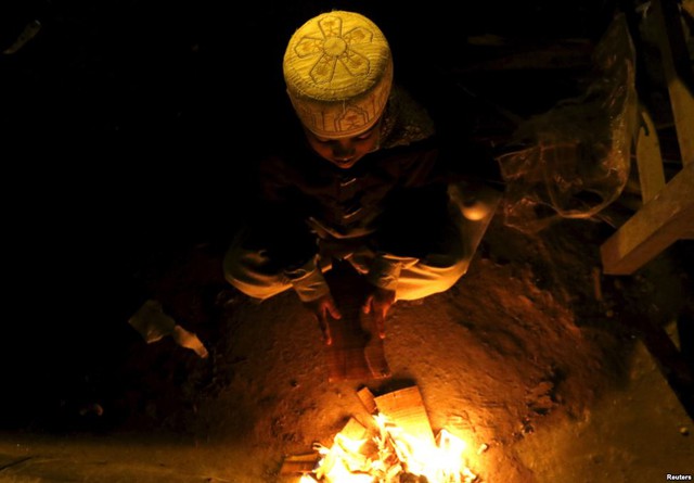 Trẻ em đốt những mảnh gỗ nhặt được trong thùng rác để sưởi ấm trên đường phố ở Peshawar, Pakistan.