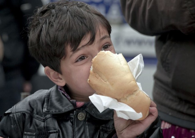 Cậu bé vô gia cư cắn ổ bánh mì bên ngoài nhà ga tàu hỏa ở thành phố Bucharest, Romania.