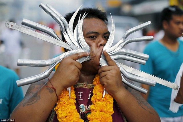 Rất nhiều người đàn ông đội các vòng hoa quanh cổ trong khi đâm xuyên nhiều vật khác nhau, trong đó có những thanh kim loại có răng cưa, qua má. (Nguồn: Reuters)