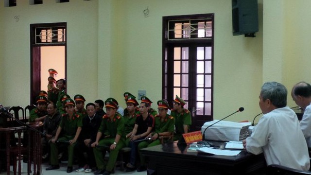 Cậu Thủy ngồi giữa các cảnh sát tư pháp bảo vệ phiên tòa - Ảnh: Quốc Nam