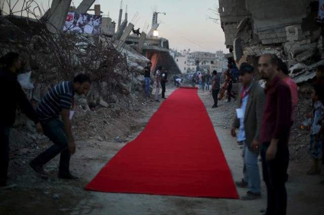 
Người dân Palestine trải một tấm thảm đỏ giữa những ngôi nhà đổ nát ở phía đông của thành phố Gaza trước buổi chiếu một bộ phim về đề tài chiến tranh ngày 12-5. Các nhân chứng cho biết khu vực này đã bị phá hủy bởi pháo kích của Israel trong một cuộc chiến kéo dài 50 ngày vào mùa hè năm ngoái.

