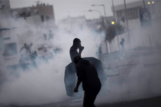 Người biểu tỉnh đứng giữa màn khói hơi cay trong cuộc đụng độ với cảnh sát chống bạo động ở ngoại ô thị trấn Manama, Bahrain.