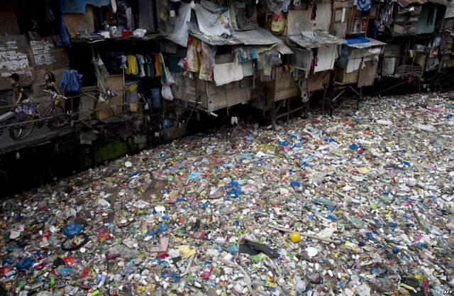 Trẻ em chơi bên bờ sông ngập rác thải ở Manila, Philippines.