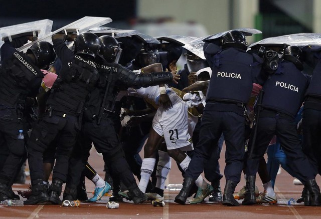 Cảnh sát chống bạo động che chắn cho các cầu thủ của đội tuyển bóng đá Ghana khỏi các vật thể do cổ động viên đội tuyển Guinea Xích đạo ném xuống trong trận bán kết 1 tại giải CAN 2015 ở Malabo, Guinea Xích đạo.