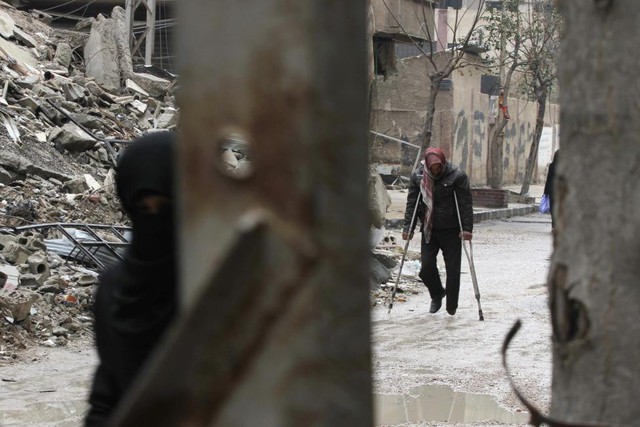 Người đàn ông chống lạng đi qua đống đổ nát của các tòa nhà tại thành phố Damascus, Syria.
