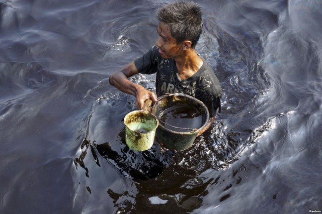 Ngư dân thu gom dầu thô rò tỉ trên biển ở Cilacap, tỉnh Java, Indonesia.