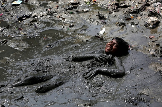 Cậu bé tắm bùn trên bờ sông Hằng ở Kolkata, Ấn Độ.