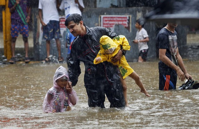 Người đàn ông tắt con đi qua đường phố ngập lụt dưới trời mưa ở Mumbai, Ấn Độ.